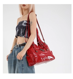Macro shot of large red tote bag with glossy finish and gothic cross metal buckle detail