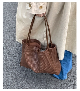 Detail of dark brown woven tote bag showing leather texture and wide strap design