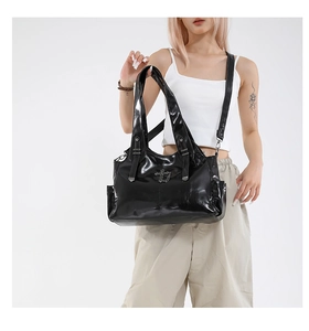 Detail of black glossy tote bag featuring vintage metal cross and side storage pockets