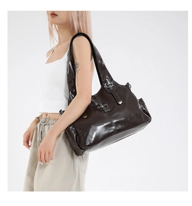 Close-up of glossy leather tote bag featuring metallic silver cross details and pockets