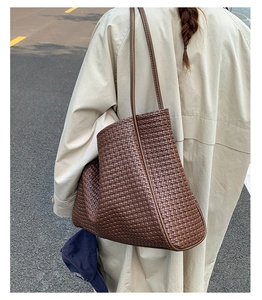 Detail of dark brown woven tote bag showing premium crisscross texture and shoulder strap