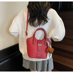 Red lychee pattern bucket bag with metal buckle and cute brown bear pendant on a model
