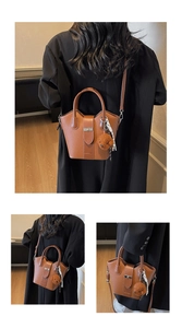 Close-up of brown bucket bag with lychee texture leather and plush bear charm decoration