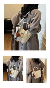 Detail of cream bucket bag featuring lychee grain leather, bear charm and silk scarf wrap