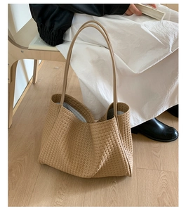 Detailed view of the woven khaki tote bag with fine cross-weave texture and thin straps