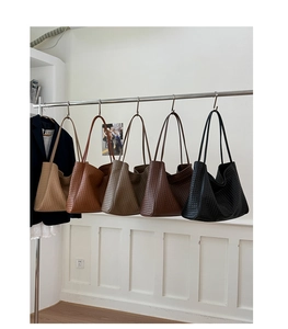 Detailed row of woven leather tote bags in khaki, brown, grey and black on a metal rack