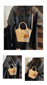 Beige bucket bag with silver twist lock, plush puppy charm, and silk scarf detail
