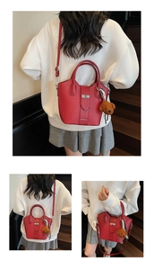 Detail of red lychee grain leather bucket bag with silver lock and bear charm