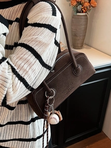 Braune Wildleder-Schultertasche mit Kontrastnähten und Baseball-Anhänger im Lifestyle