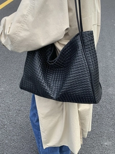 Chic black woven leather tote bag shown in a street style street wear context