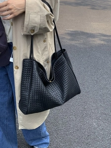 Minimalist black woven tote bag with slim shoulder straps and large capacity for commuting