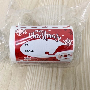 Close-up of Christmas gift label roll with Santa Claus design and To/From writing space
