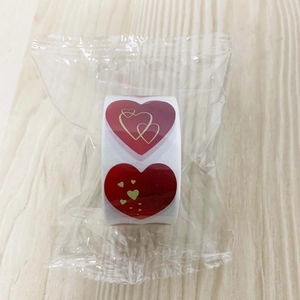 Detail of red heart roll stickers with gold line patterns on light wood surface