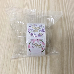 Close-up of circular floral thank you stickers in purple and pink tones with gold script