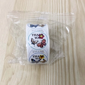 Close-up of butterfly thank you stickers roll for wedding and party favors on wood table
