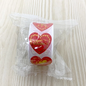 Macro shot of 1-inch red and gold heart stickers roll for Valentine's Day gift sealing
