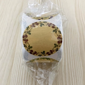 Détail d'autocollants ronds en kraft avec motif couronne florale sous emballage plastique