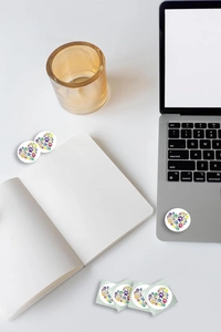 Rainbow animal paw print heart stickers on a laptop and notebook in a bright desk setting