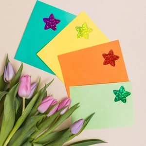 Macro shot of glitter star stickers on colorful envelopes with tulip decoration