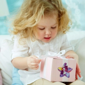 Close-up of galaxy star stickers decorating a pink gift box held by a young girl