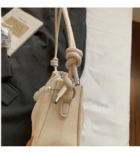 Détail du sac nuage beige avec chaîne de perles et bandoulière élégante avec nœud décoratif