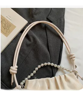 Détail du sac nuage avec anse en perles et texture plissée sur un blazer gris