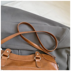 Detailed close-up of brown leather bag with silver metal ring and fine stitching detail