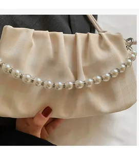 Détail du sac plissé crème avec motif à carreaux et poignée en perles fantaisie