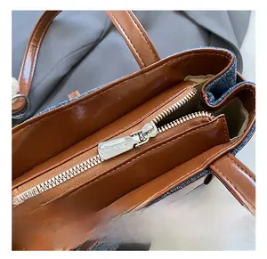 Detail des silbernen Metallreißverschlusses und braunem Lederbesatz auf Denim-Tasche