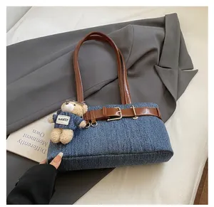 Détail du sac à épaule en jean bleu avec boucle en cuir marron et pendentif ourson