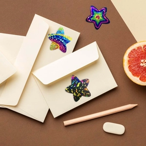 Detail of holographic star stickers with glitter finish on beige envelopes