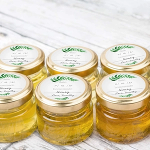 6-pack small glass honey jars with gold metal lids and homemade stickers on wood surface