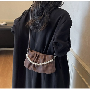 Détail du sac nuage à carreaux marron avec chaîne en perles et plis sur manteau noir