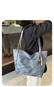 Detail of grey-blue vintage tote bag with wooden bead charm and long shoulder strap