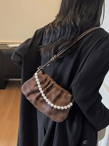 Sac nuage à damier marron avec chaîne de perles porté à l'épaule par un mannequin