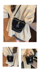 Detail of minimalist black suede bucket bag featuring leather trim and gold metal hardware