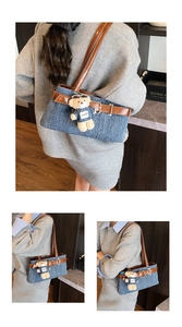 Details der blauen Jeans-Schultertasche mit braunen Lederriemen und süßem Bärenanhänger