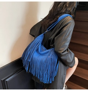 Dettaglio della borsa a tracolla blu reale con frange e trama scamosciata su modella