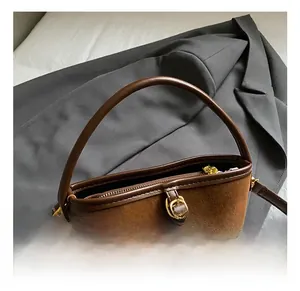 Detail showing high-quality matte suede leather texture and golden metal buckle on brown bag