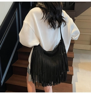 Vista dettagliata di una borsa hobo nera con frange e lunghe nappe bohémien su una modella