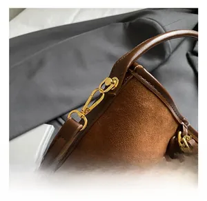 Macro detail of the premium gold hardware and contrast leather stitching on brown bucket bag