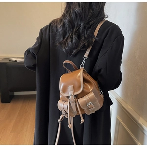 Rear view of model wearing a vintage brown faux leather mini backpack with dual pockets