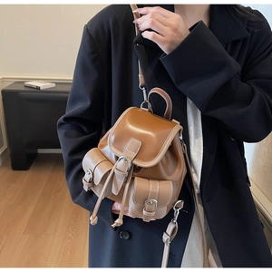 Side view of a vintage brown leather mini backpack with contrast stitching and pockets