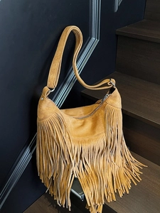 Borsa hobo bohémien in camoscio marrone con frange e tracolla larga in ambiente interno
