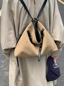 Khaki suede shoulder bag with black leather straps and gold buckle in outdoor street view