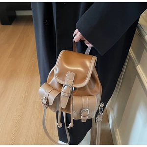 Close-up of vintage brown leather mini backpack with metal buckles and white stitching