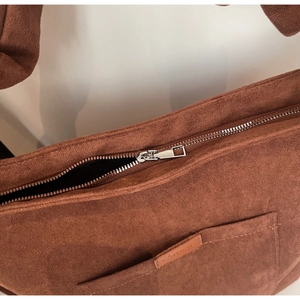 Macro shot of brown faux suede texture with metallic silver zipper and logo tag