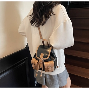 Detail view of vintage denim backpack with brown leather trim and buckle side pockets