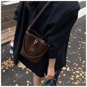 Outdoor-Streetstyle-Foto einer dunkelbraunen Wildleder-Beuteltasche zu einem schwarzen Blazer