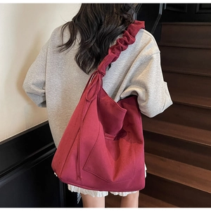 Detail of burgundy canvas tote bag with ruffled wide strap and side pocket for women